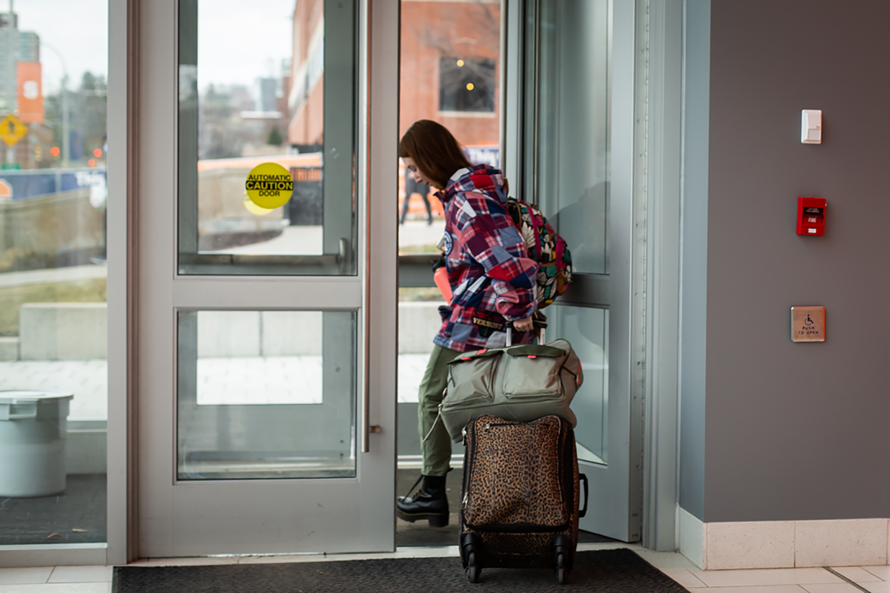 Student pulling suitcase through door